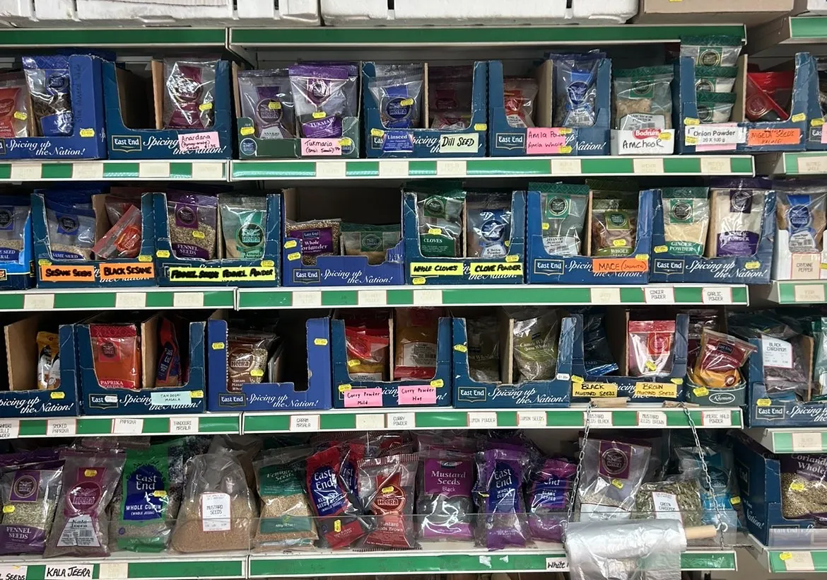 A wall of whole spice packets in labelled shelf boxes